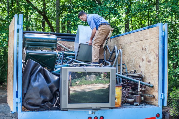 Worker loading old electronics and scrap items into a trailer for E waste removal services Kent WA